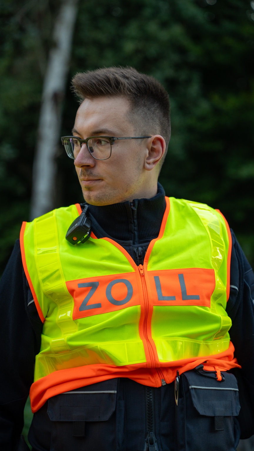 Porträt eines Mannes mit Brille und gelber Zoll-Warnweste im Wald