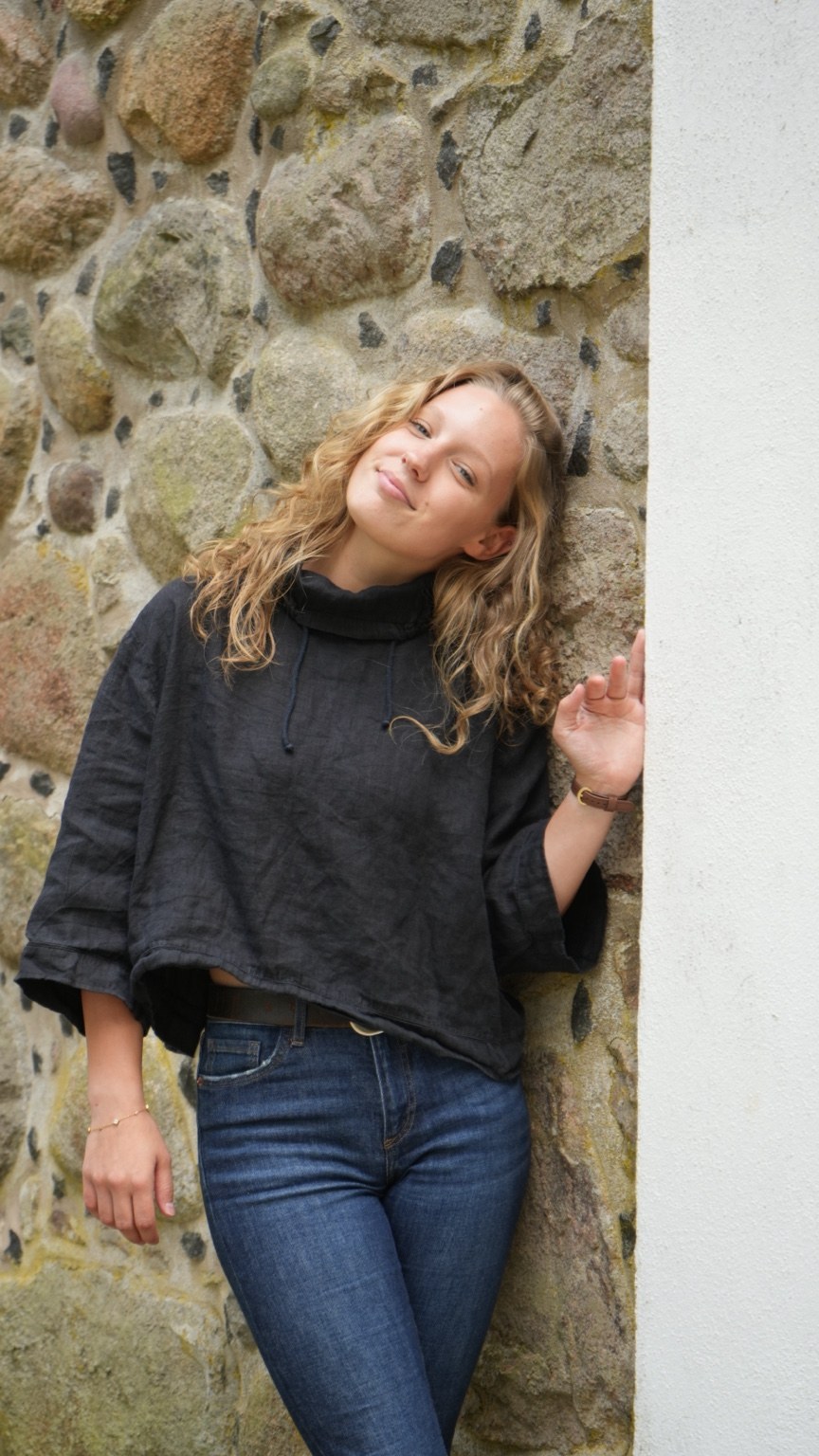 Frau in schwarzer Bluse an einer historischen Steinmauer